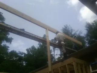 Carpenter setting a ridge beam over a new addition frame — Ice Dam Removal by Roofing Brothers in Skippers