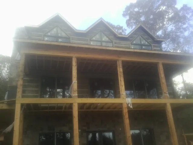 Dormers and porch framing on a large log home under construction — Roof Coating work by our crew in Skippers