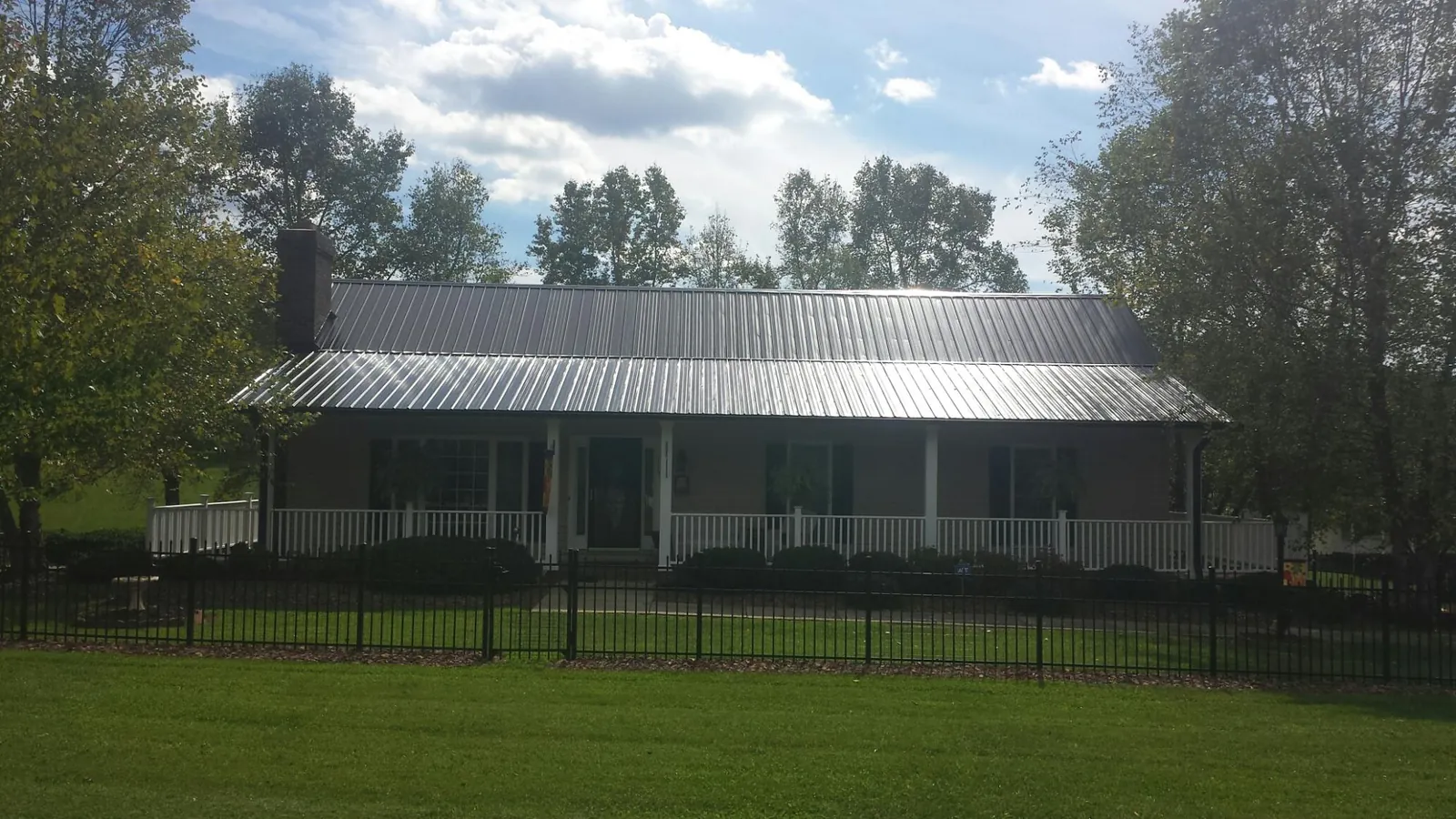 Gray metal roof on a brick ranch with a full width front porch — Gutter Guard Installation work by our crew in Skippers