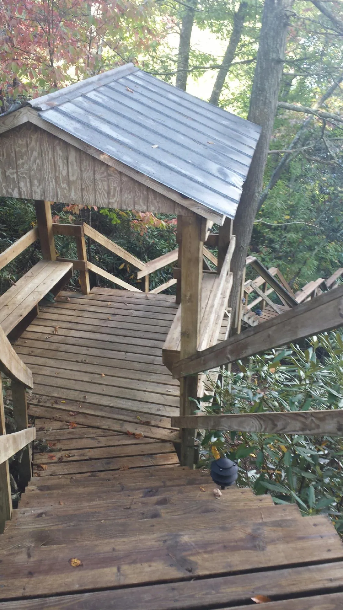 Metal roofed shelter over wooden steps on a wooded walkway — Skylight Repair & Installation work by our crew in Skippers
