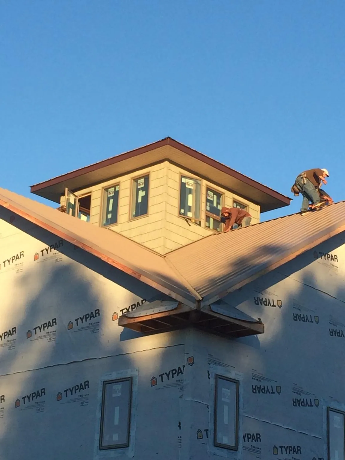 Roofers working around a rooftop cupola on a new metal roof at sunset — Roof Waterproofing in Skippers by Roofing Brothers